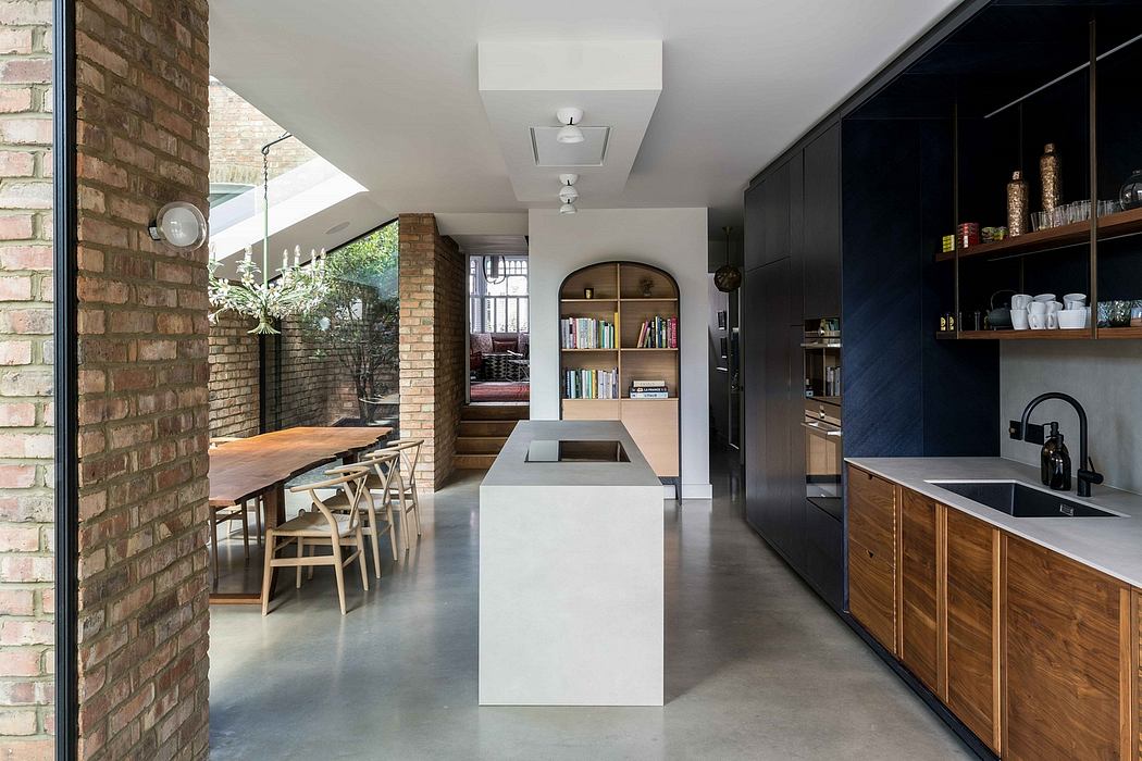 A modern kitchen with sleek black and wood cabinetry, concrete floors, and an arched entryway.