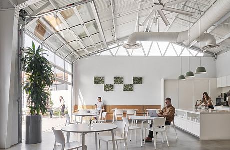 Spacious modern office with high ceilings, glass walls, and minimalist furnishings.