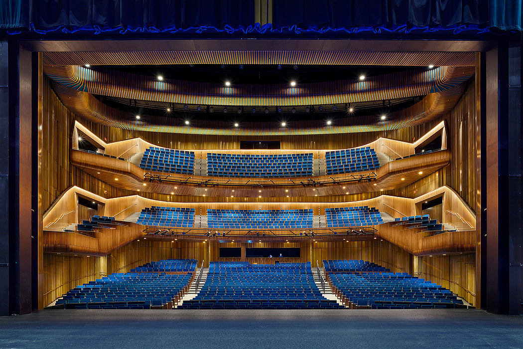 An ornate, tiered performance hall with blue seating and warm wooden accents.