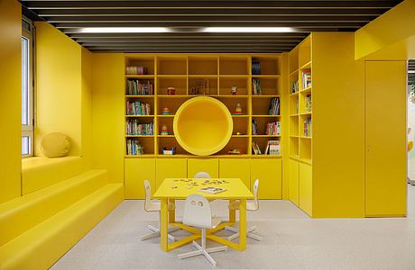 Vibrant yellow-toned interior with built-in shelving, circular window, and minimalist furniture.