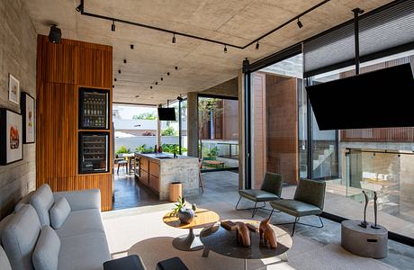 Spacious open-plan living area with concrete walls, wooden panels, and modern furnishings.