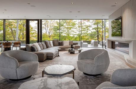 Spacious modern living room with panoramic windows overlooking lush greenery.