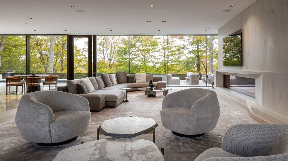 Spacious modern living room with panoramic windows overlooking lush greenery.
