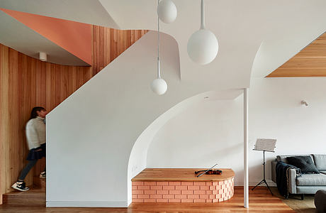 Curvaceous white walls, hardwood floors, and geometric pendant lights create a modern interior.