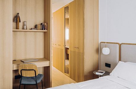 Modern, wood-paneled bedroom with built-in storage, desk, and minimalist decor.