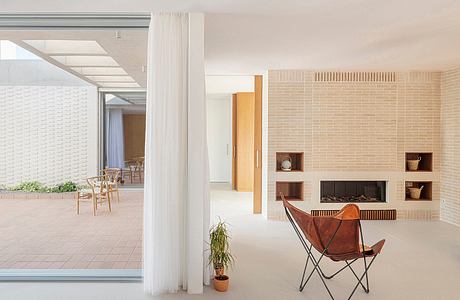 Expansive indoor-outdoor space with brick walls, open shelving, and a leather lounge chair.