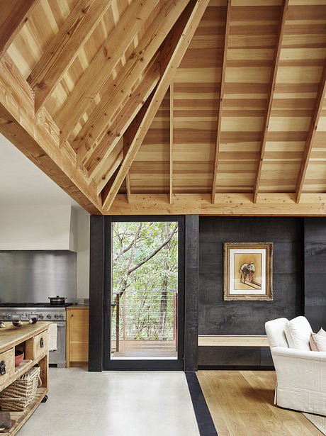 A cozy cabin interior with wooden beams, sleek dark walls, and a framed artwork.