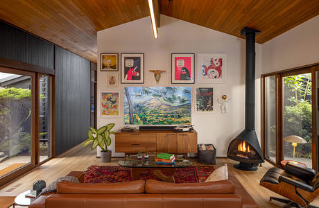 Cozy midcentury living room with wood-paneled ceiling, fireplace, and eclectic decor.