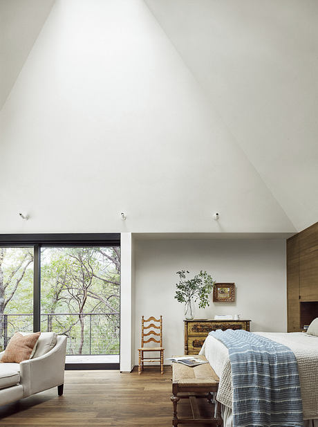 Spacious bedroom with high ceilings, large windows, and rustic furnishings.