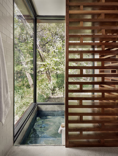 A cozy indoor hot tub surrounded by large windows and a wooden slatted wall.