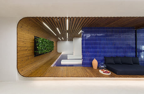 A modern, minimalist interior design featuring wooden slats, a living wall, and vibrant blue tiles.