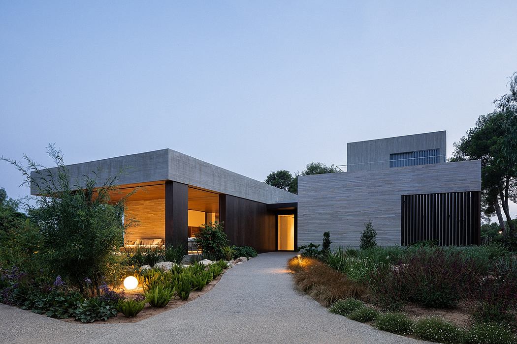 Contemporary concrete and wood home exterior with illuminated entryway and landscaped garden.