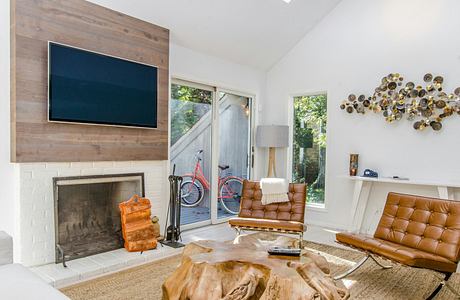 Rustic living room with wood-paneled walls, fireplace, and modern leather furniture.