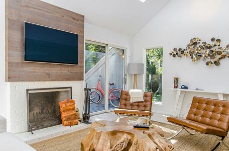 Rustic living room with wood-paneled walls, fireplace, and modern leather furniture.