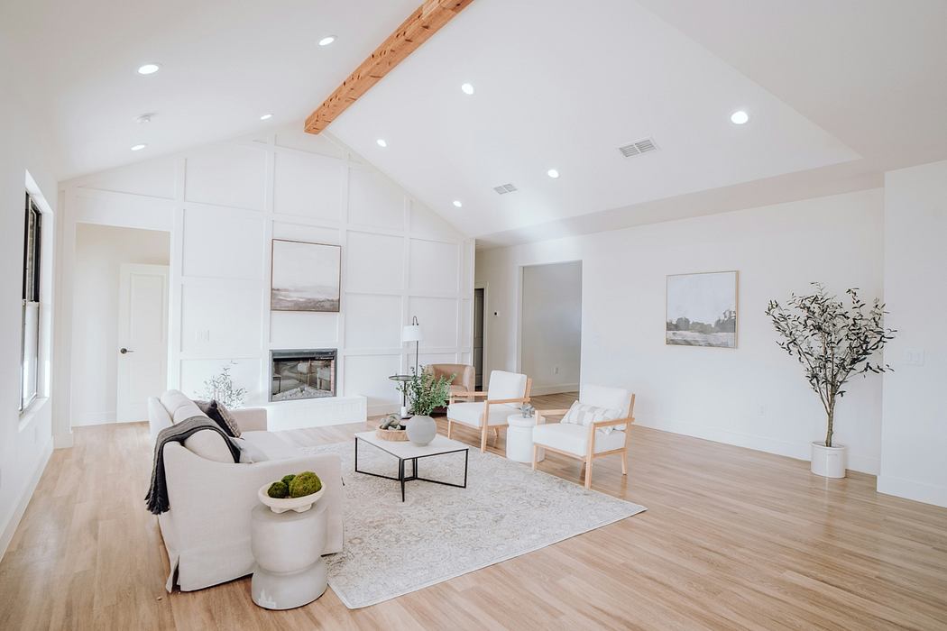 Bright, airy living room with vaulted ceilings, wood beams, and minimalist furniture.