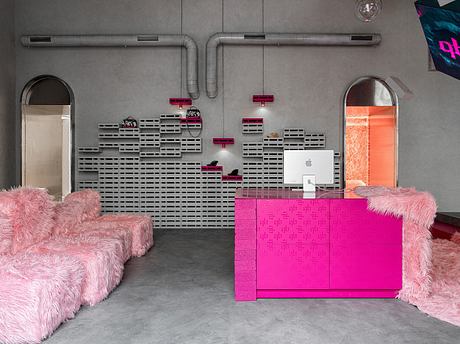 A modern, minimalist interior with bold pink furniture, industrial pipes, and concrete walls.