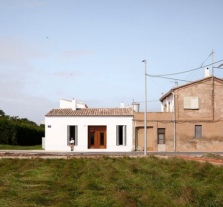 Quaint rural buildings with traditional tile roofs and an open doorway, set against a grassy field.