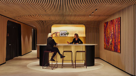 A modern, minimalist reception area with curved wooden wall panels and a sleek counter.