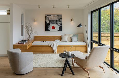 Cozy living space with wooden platform bed, plush seating, and nature-inspired artwork.