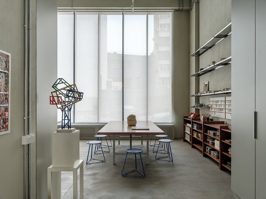 Bright, minimalist workspace with geometric sculptures, wooden table, and metal shelving.