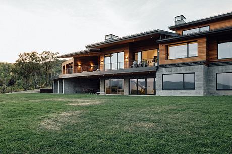 A modern, multi-story home with expansive windows, wood accents, and a large patio.