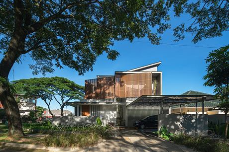 Contemporary residential building with wooden slat facade, shaded courtyard, and carport.