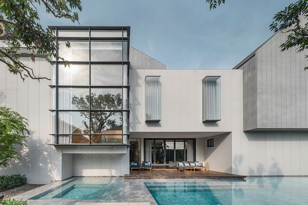 A modern residential building with a sleek, minimalist design, featuring a pool and lush greenery.