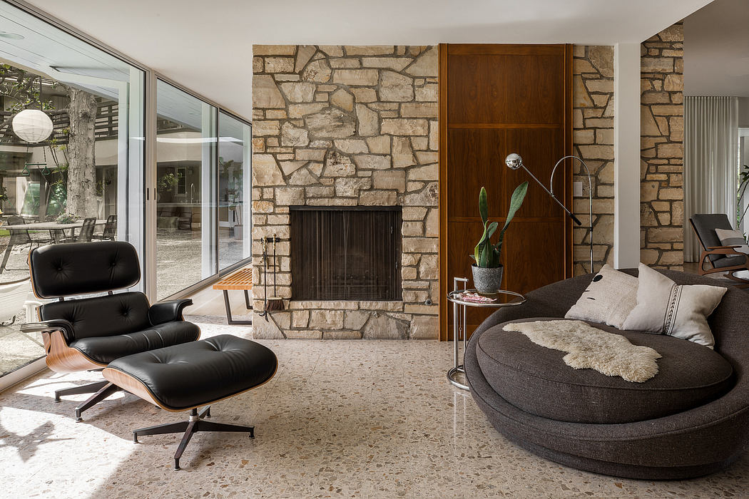 Cozy modern living room with stone fireplace, plush seating, and expansive windows.