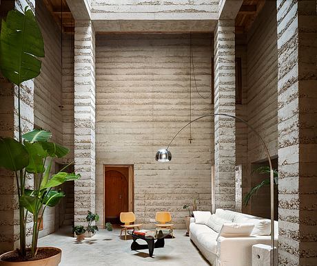 Minimalist living room with exposed concrete walls, arched doorway, and modern furnishings.