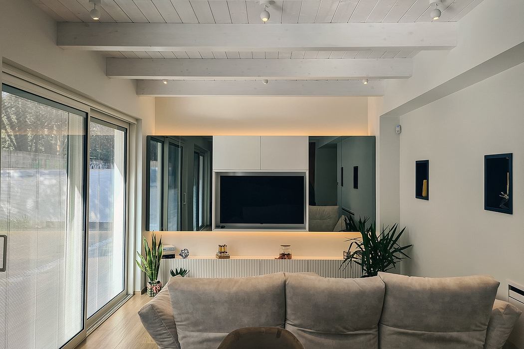 Minimalist living room with exposed beams, large TV, and sleek furniture.