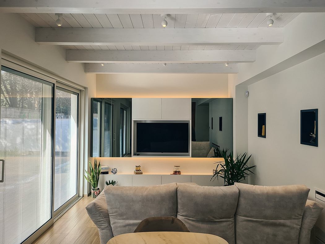 Minimalist living room with exposed beams, large TV, and sleek furniture.