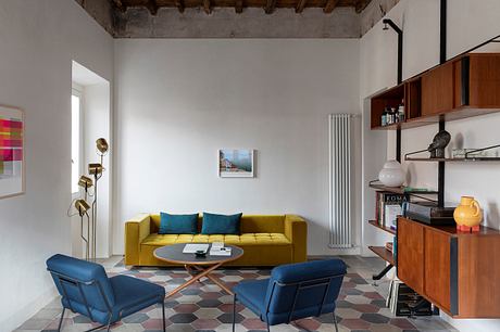 Spacious living room with wooden beams, plush yellow sofa, and geometric tile flooring.