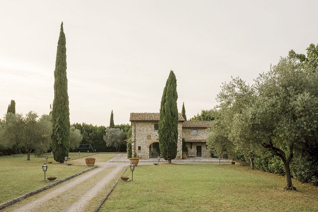 An idyllic Tuscan villa with cypress trees, stone walls, and a grassy courtyard.