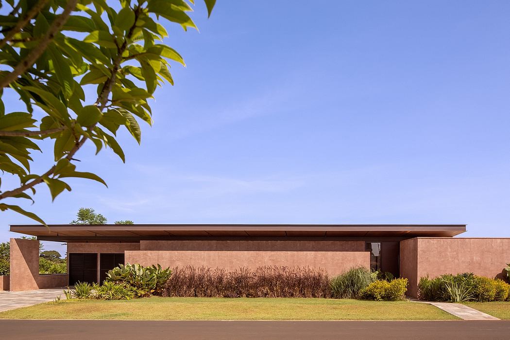 A modern one-story building with a flat roof, wooden beams, and lush landscaping outside.