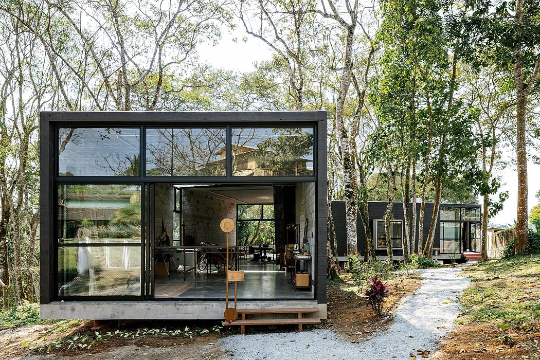 A modern glass-enclosed structure nestled in a lush forested environment, with an indoor-outdoor design.