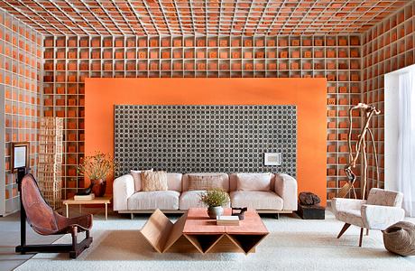 A modern, minimalist living space with a vibrant orange accent wall and geometric furniture.