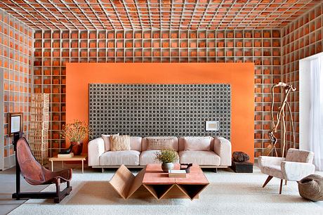 A modern, minimalist living space with a vibrant orange accent wall and geometric furniture.