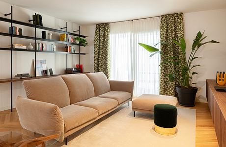 Cozy living room with beige sofa, shelving unit, and tropical plant accents.