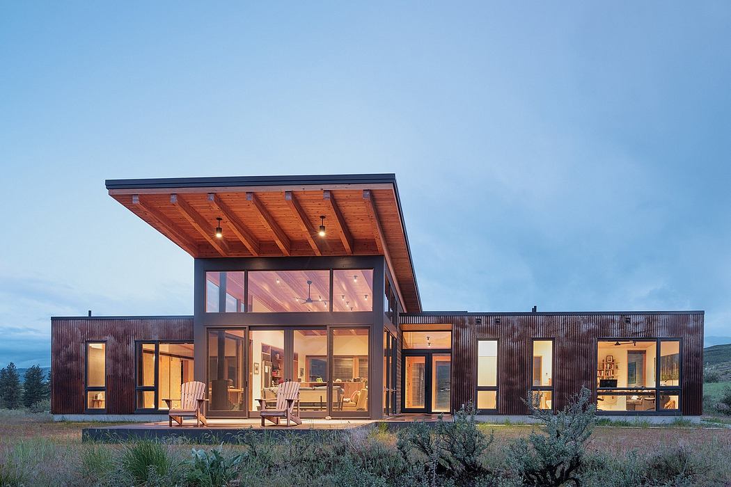 Distinctive wooden-beamed structure with expansive glass walls overlooking a rural landscape.