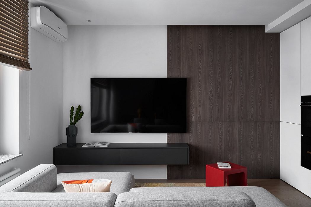 A modern living room with a large TV, dark wood panels, and a gray couch.