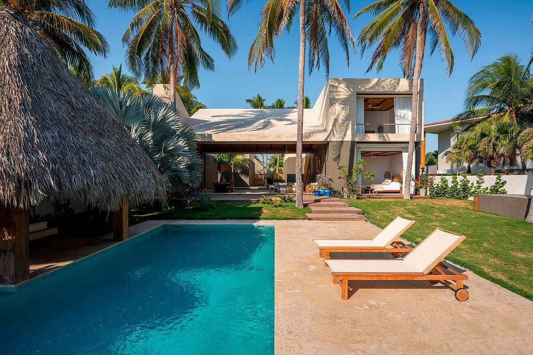 Elegant tropical beach villa with thatched roof, swimming pool, and lush landscaping.