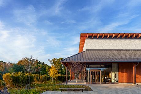 Rustic wooden building with metal roof and glass walls, surrounded by autumn foliage.