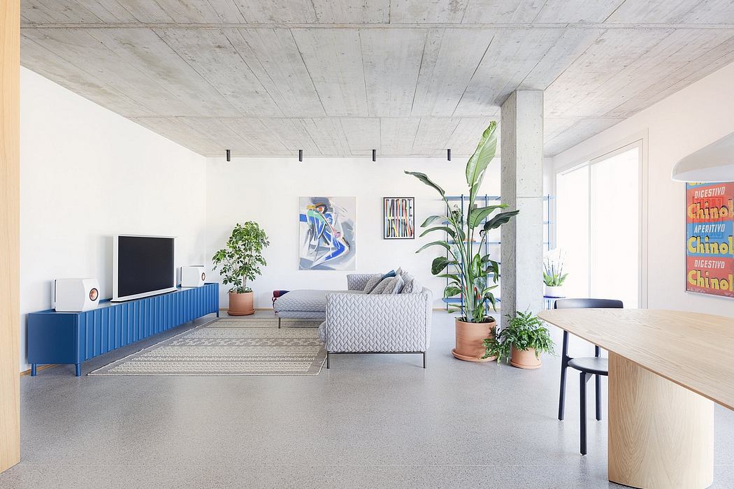 Spacious, modern living room with concrete ceiling, blue TV cabinet, and potted plants.