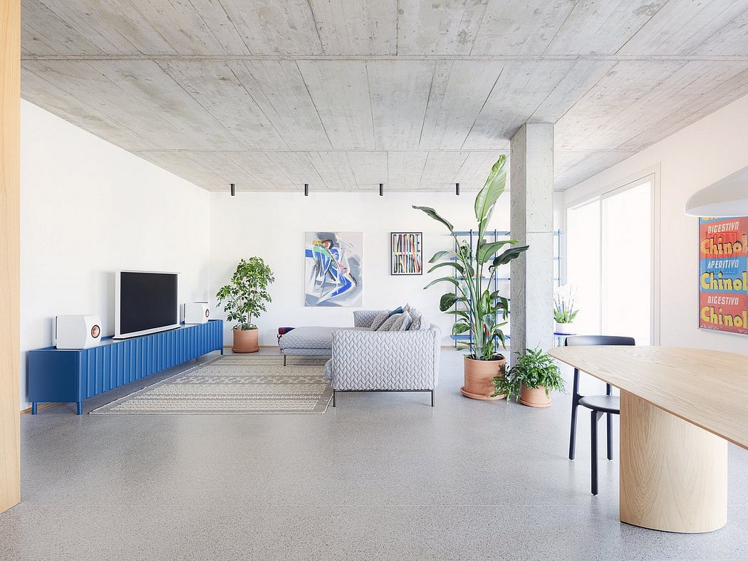 Spacious, modern living room with concrete ceiling, blue TV cabinet, and potted plants.