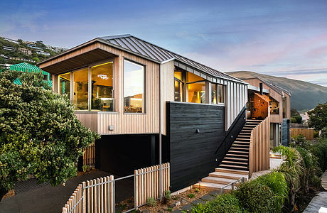 A modern, multi-level home with a sleek wooden exterior, expansive windows, and a wraparound deck.