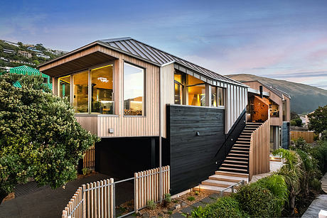 A modern, multi-level home with a sleek wooden exterior, expansive windows, and a wraparound deck.