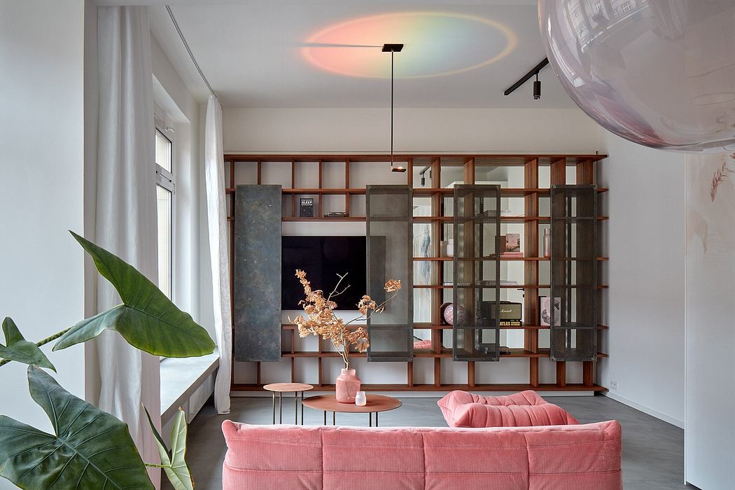 A modern living room with a wooden bookshelf wall, pink sofa, and circular lighting fixture.