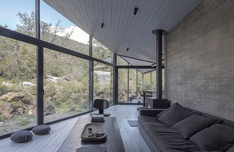 Sleek modern interior with concrete walls, large windows, and dark wooden floors.