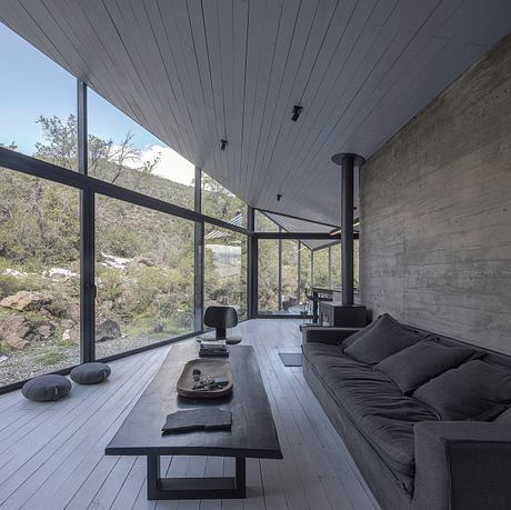 Sleek modern interior with concrete walls, large windows, and dark wooden floors.