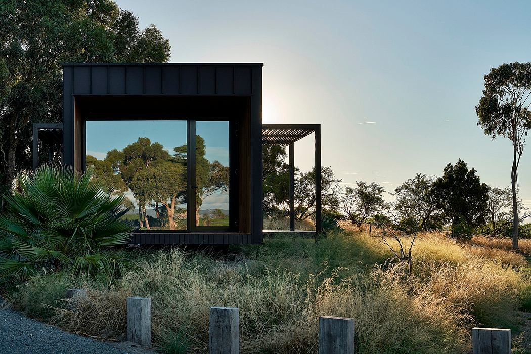 A modern, black-framed structure with large windows overlooking a natural landscape.